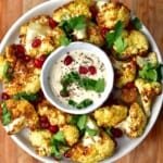 Roasted air fryer cauliflower served in a plate with a small bowl of sauce