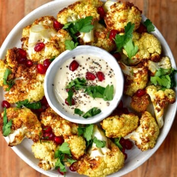 Roasted air fryer cauliflower served in a plate with a small bowl of sauce