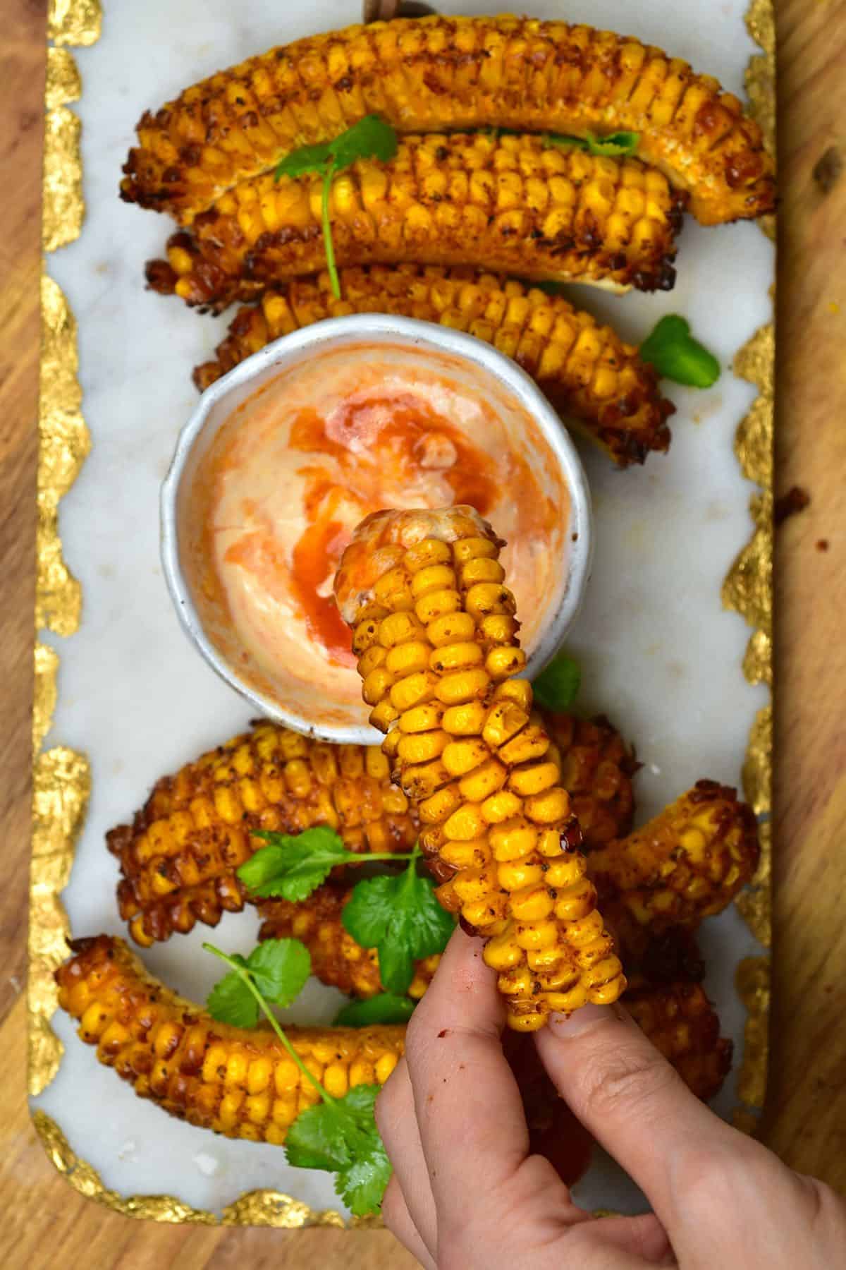 Dipping corn rib in chili mayo