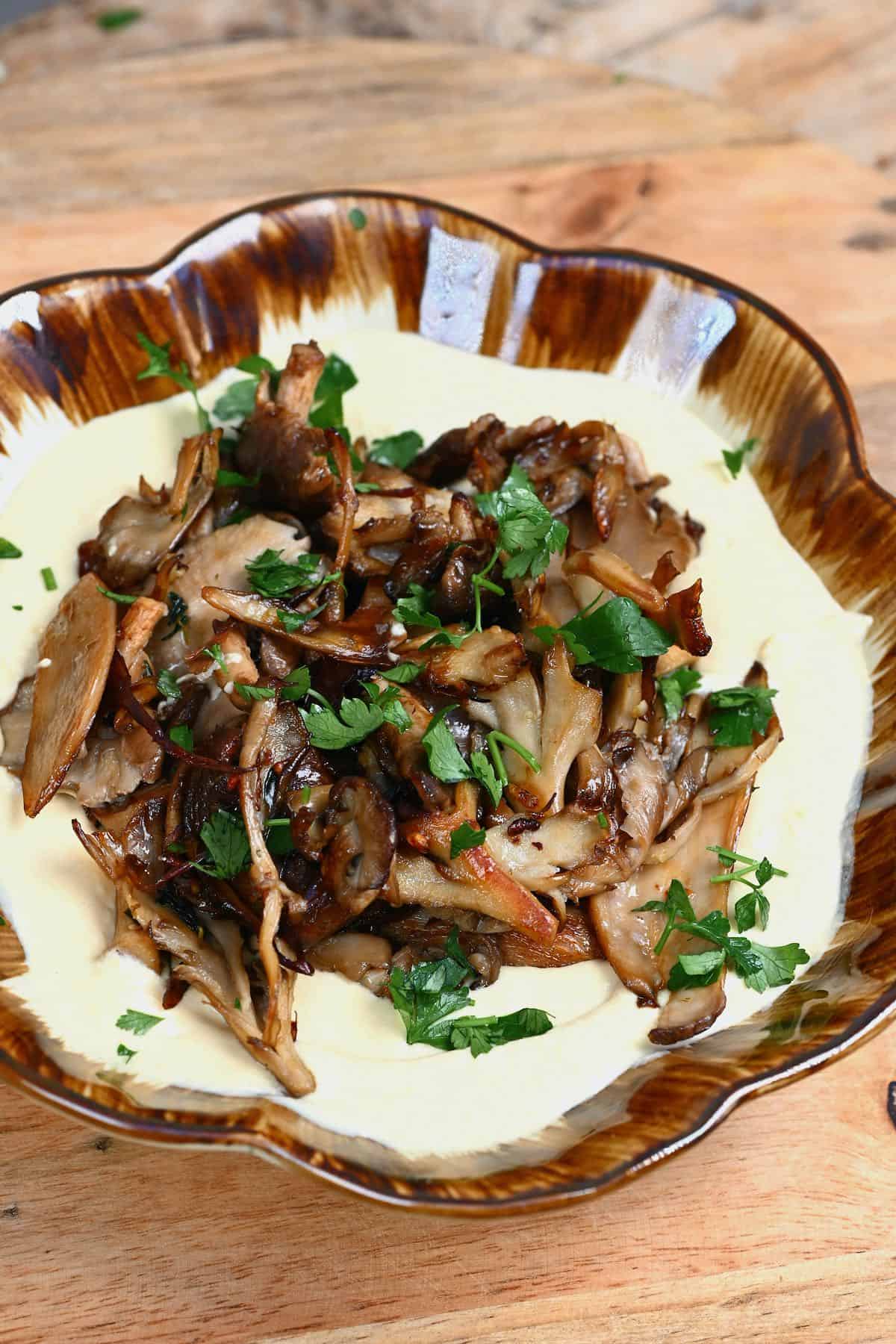 Cooked mushrooms served over hummus in a bowl