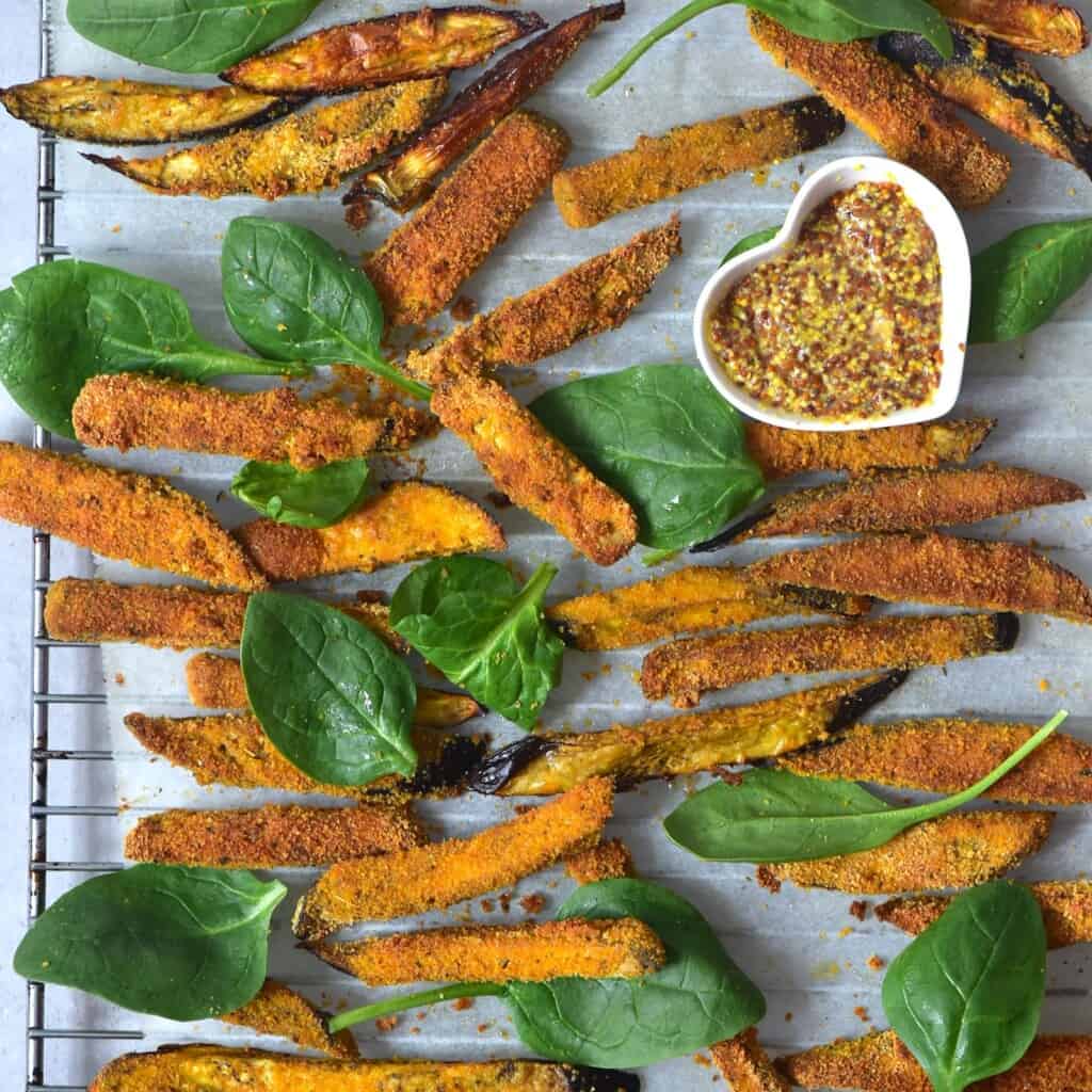 Eggplant baked fries with some spinach leaves and mustard