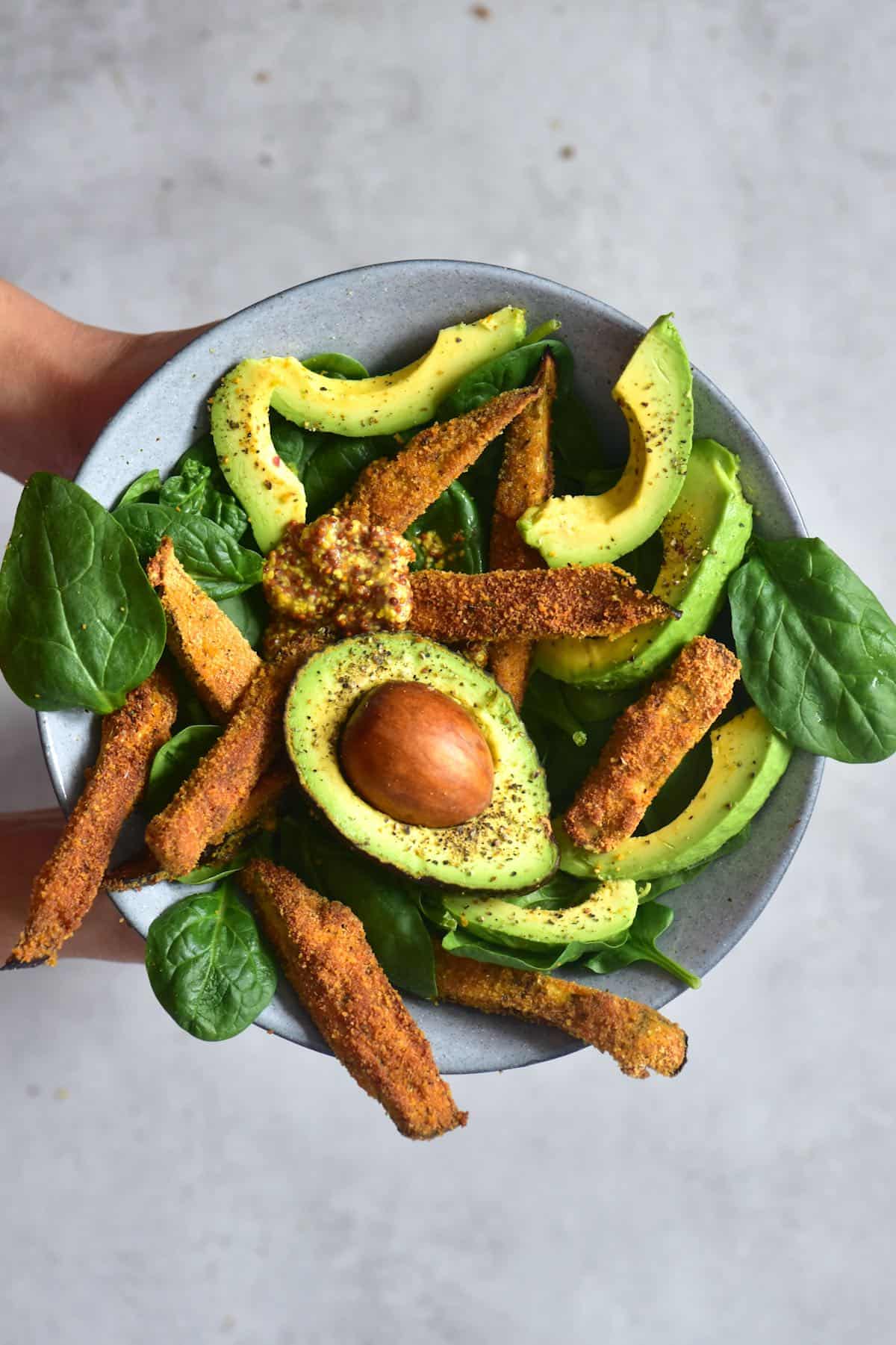 Baked eggplant fries served with spinach and avocado in a bowl