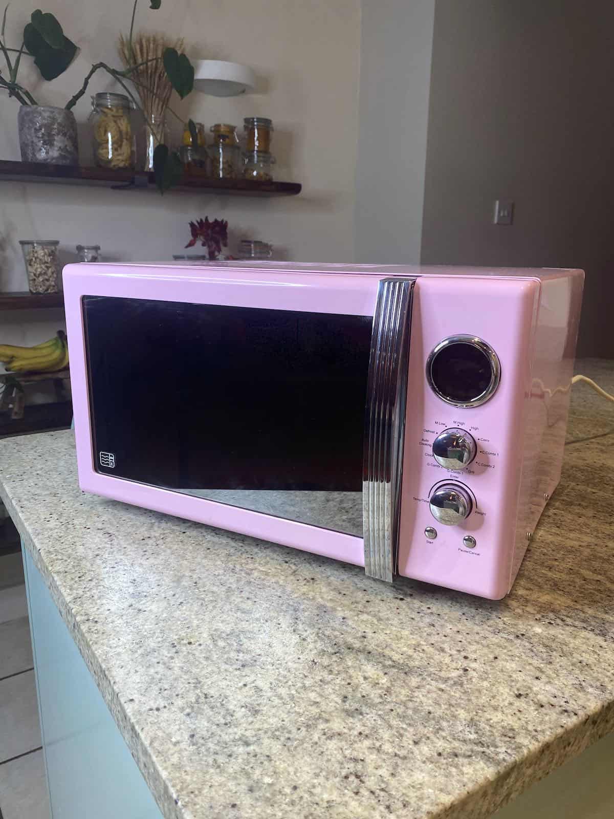 A clean pink microwave on a kitchen island