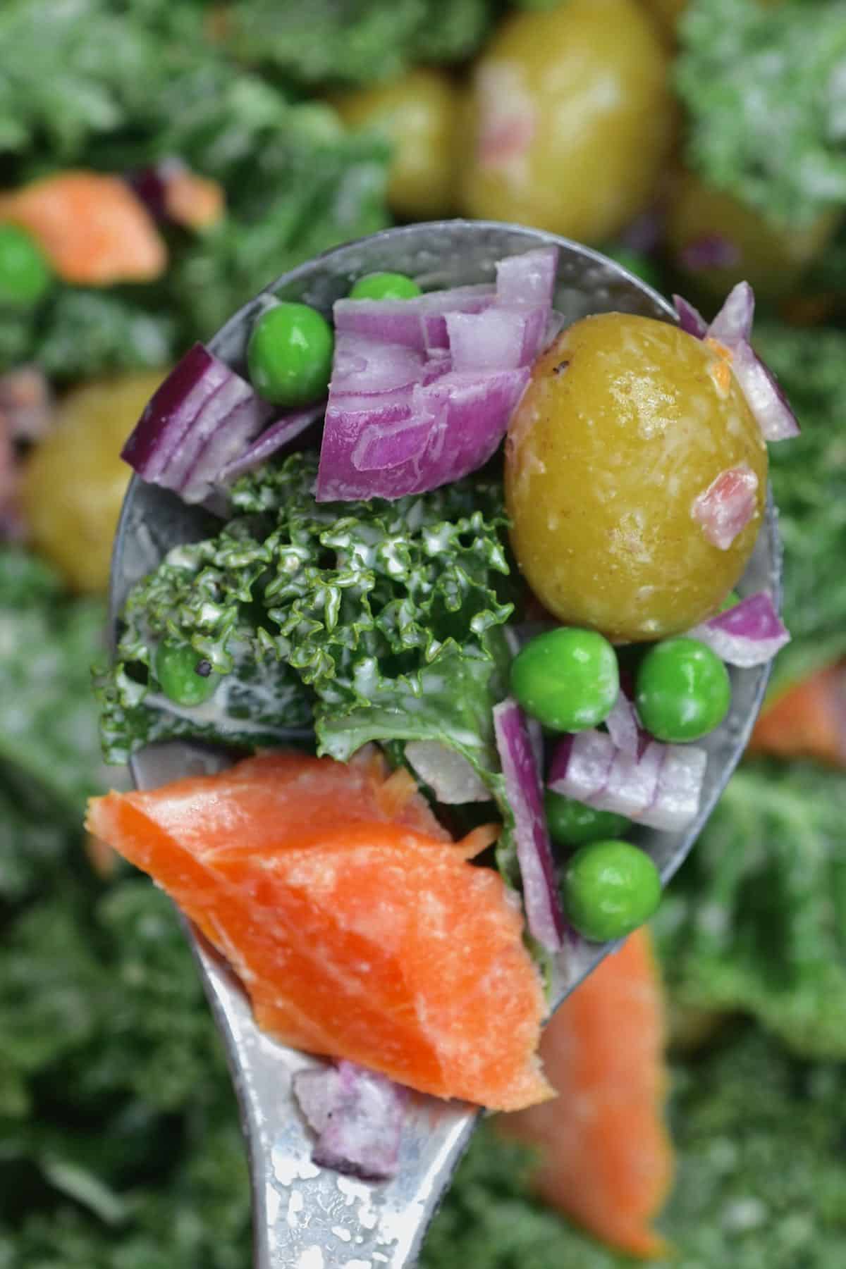 A close up of a spoonful of potato kale salmon salad