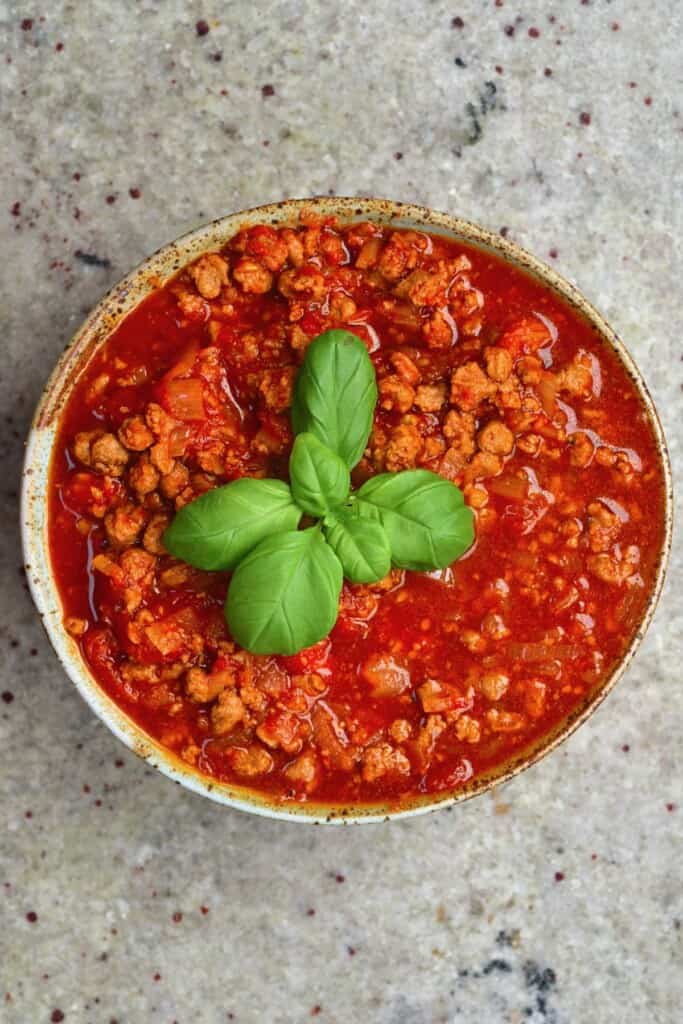 Vegan bolognese sauce in a bowl topped with basil leaves