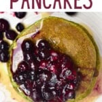 A stack of green spinach pancakes topped with berry compote
