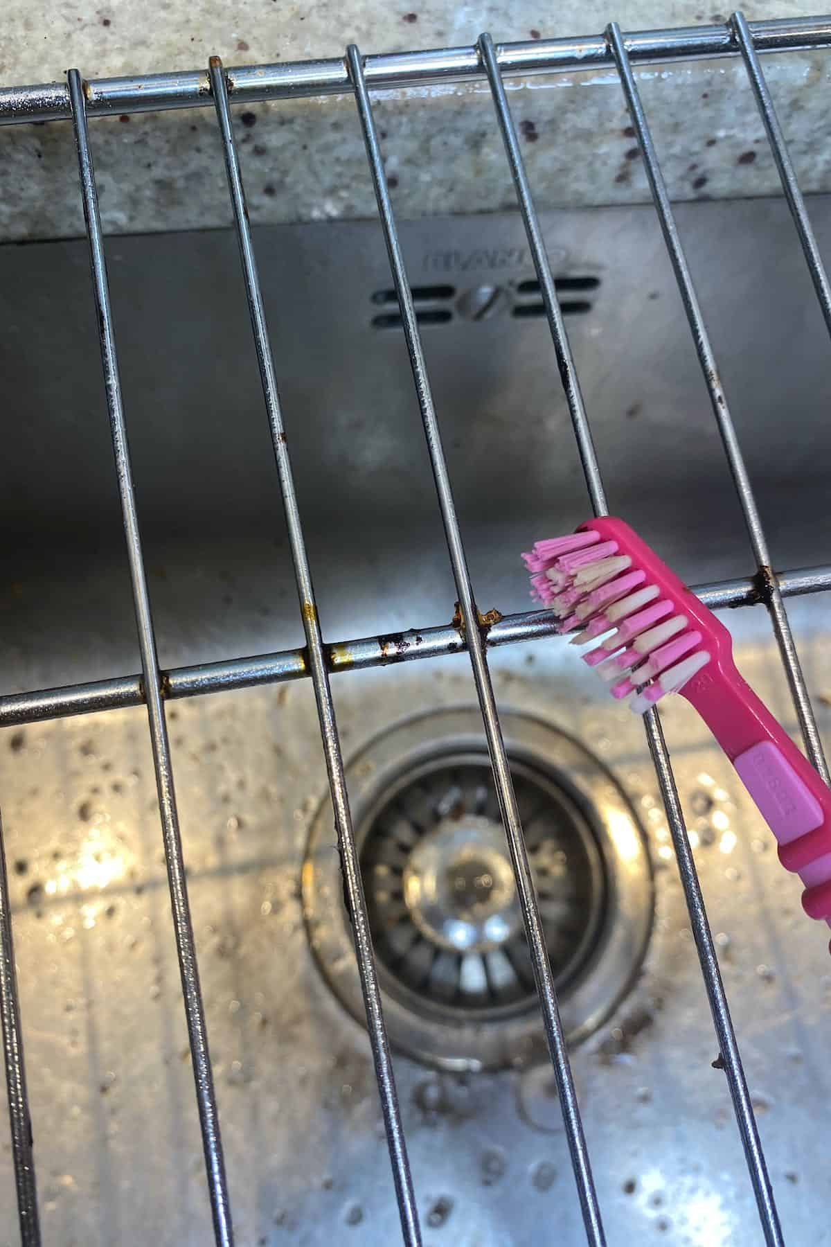 Scrubbing a baking rack with a toothbrush