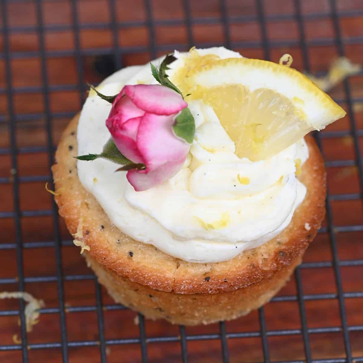 Lemon cupcake with frosting and topped with rose and lemon slice