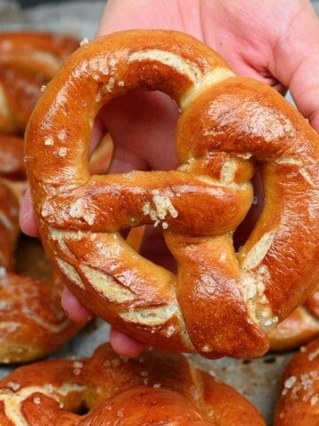 A hand holding a homemade pretzel topped with coarse salt