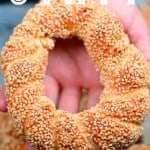 A hand holding a simit bread