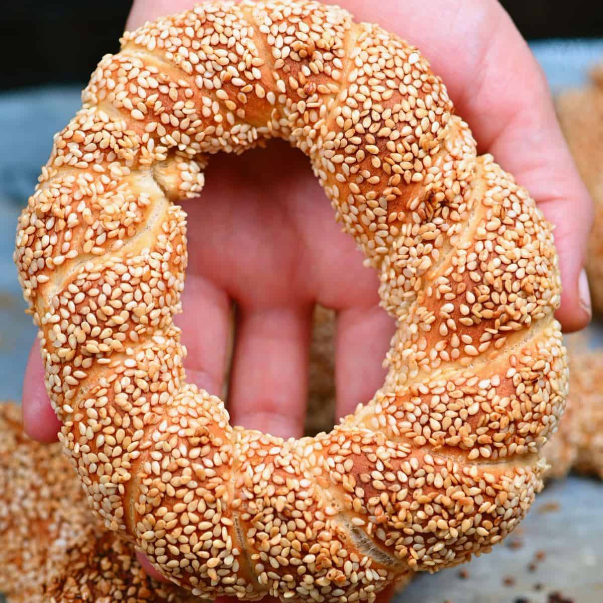 A hand holding a baked simit