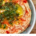White bean dip served in a pale blue bowl topped with paprika and parsley and oil