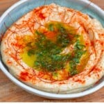 White bean dip served in a pale blue bowl topped with paprika and parsley