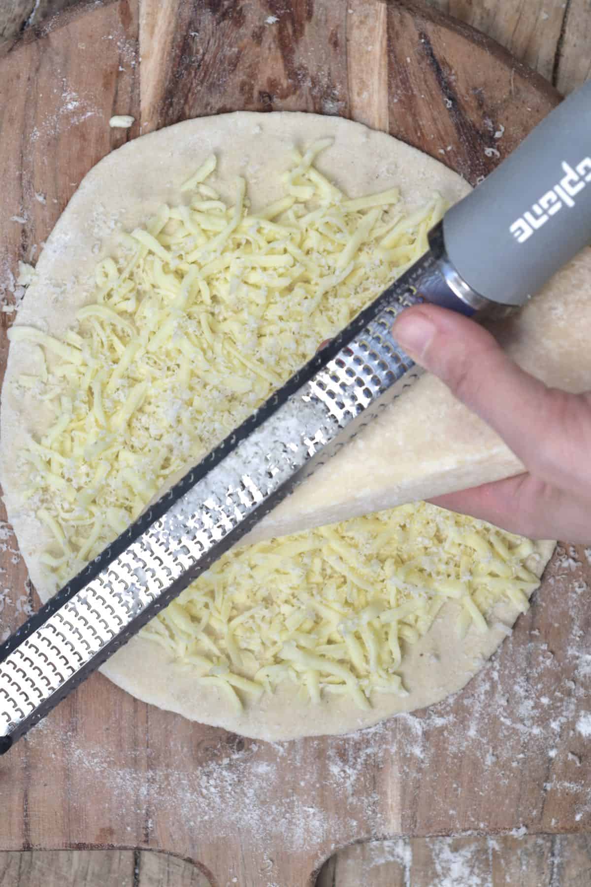Adding parmesan onto a cheese manakish