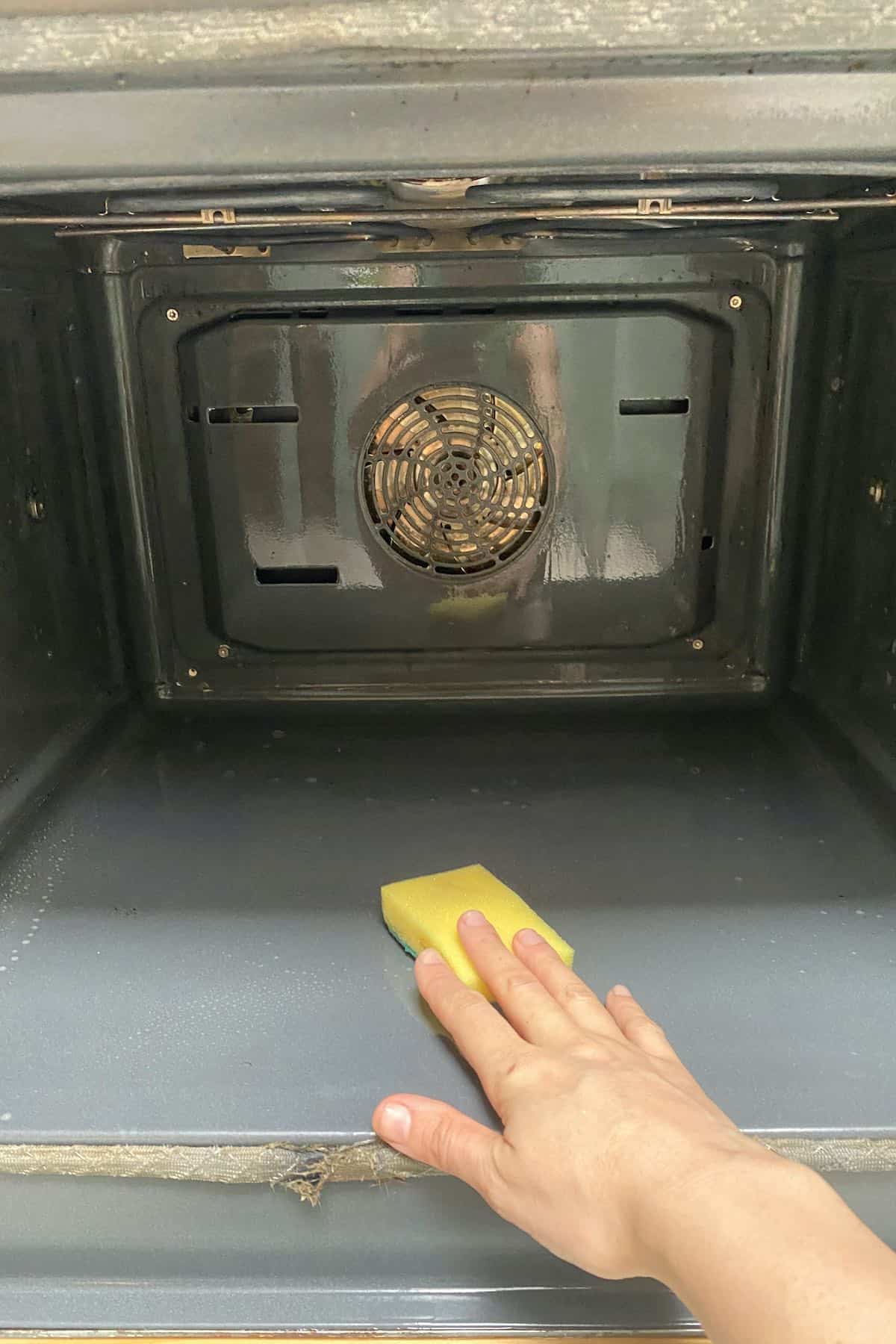 Using a sponge to clean oven