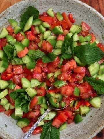 Tomato cucumber salad in a bowl with a spoon