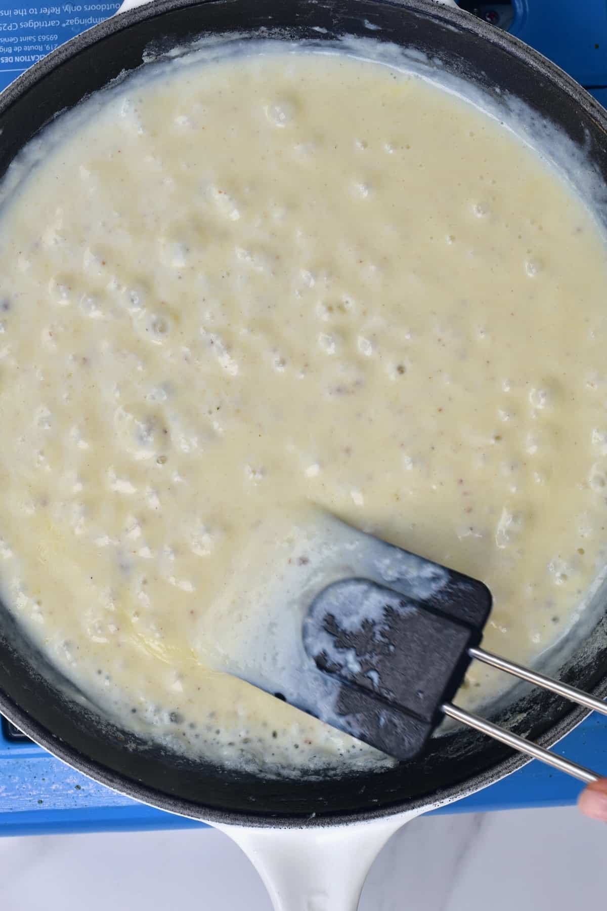Stirring bechamel sauce in a pan