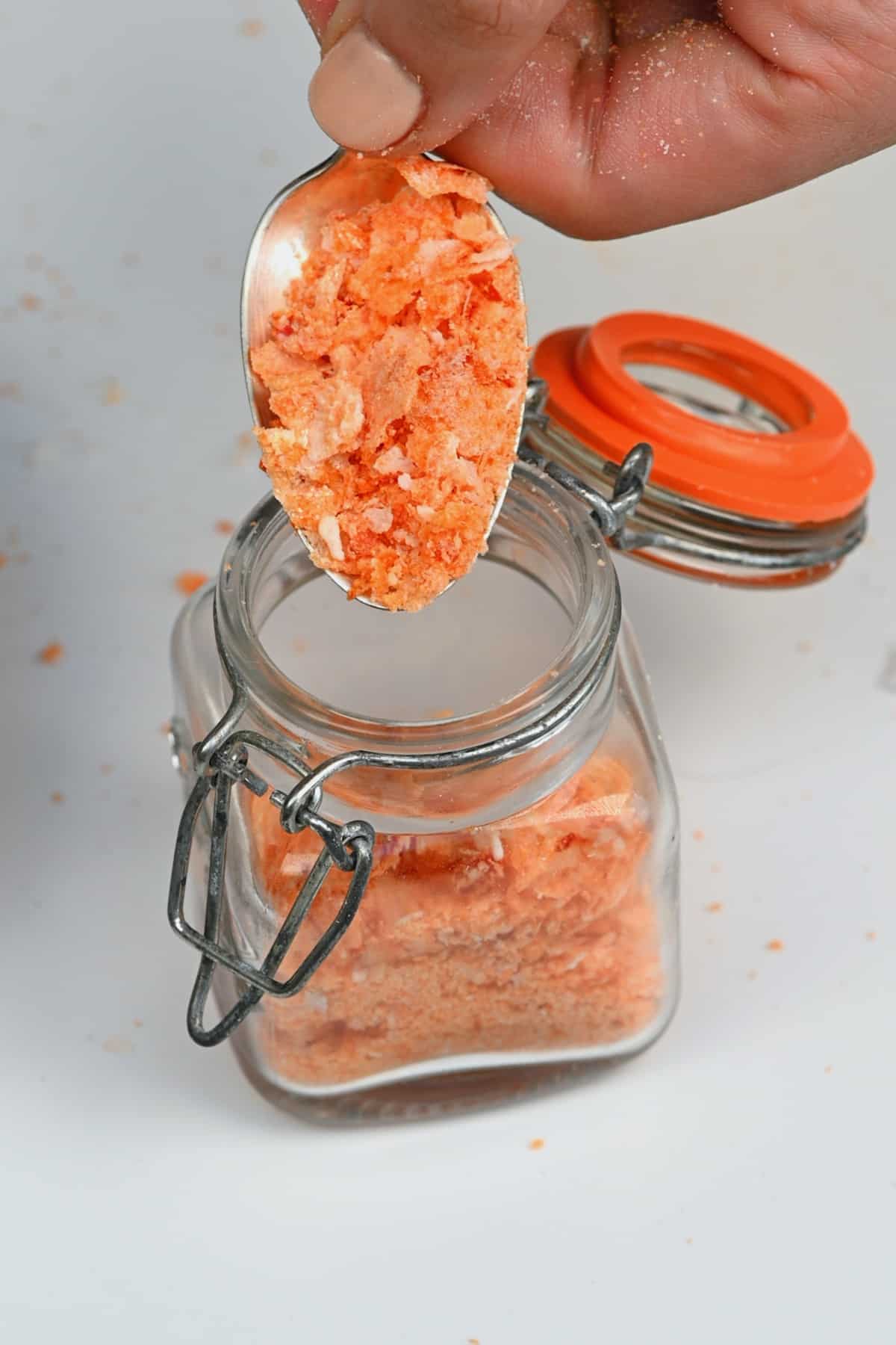 Filling a small jar with chili flaky salt