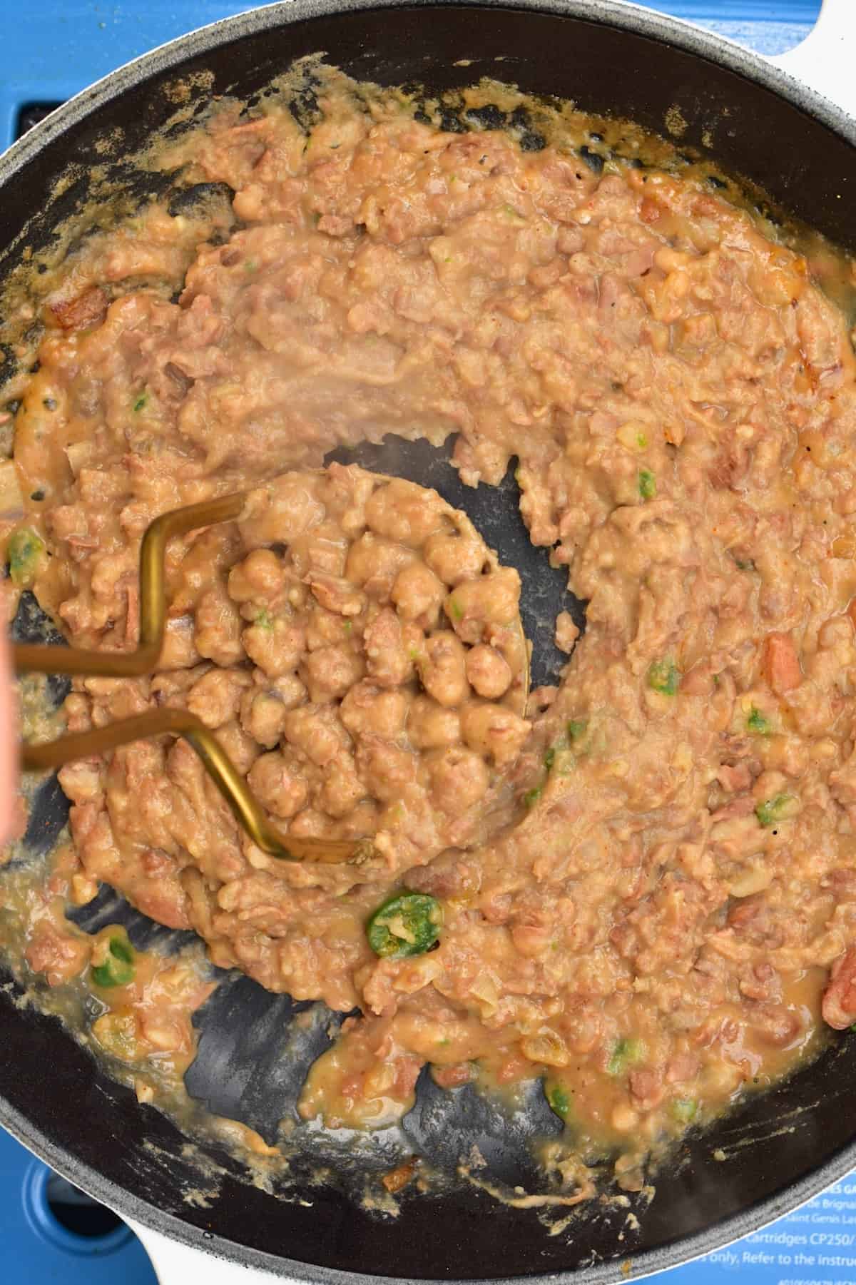 Mashing vegan refried beans in a pan