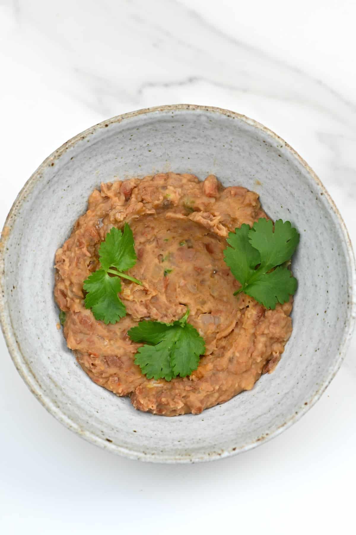 Vegan refried beans (frijoles refritos) in a bowl topped with parsley leaves