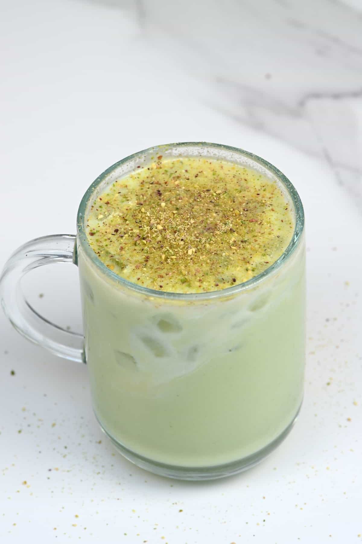 A glass with avocado shake topped with pistachio