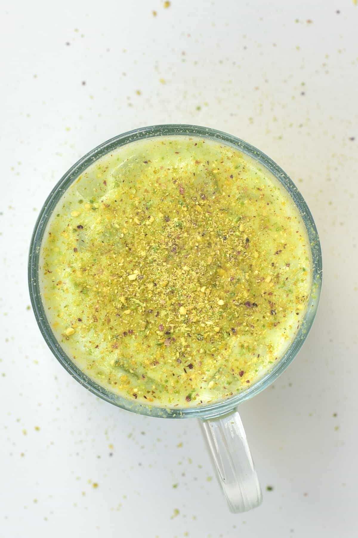 A glass with avocado shake topped with pistachio