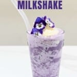 Blueberry milkshake in a glass with a straw