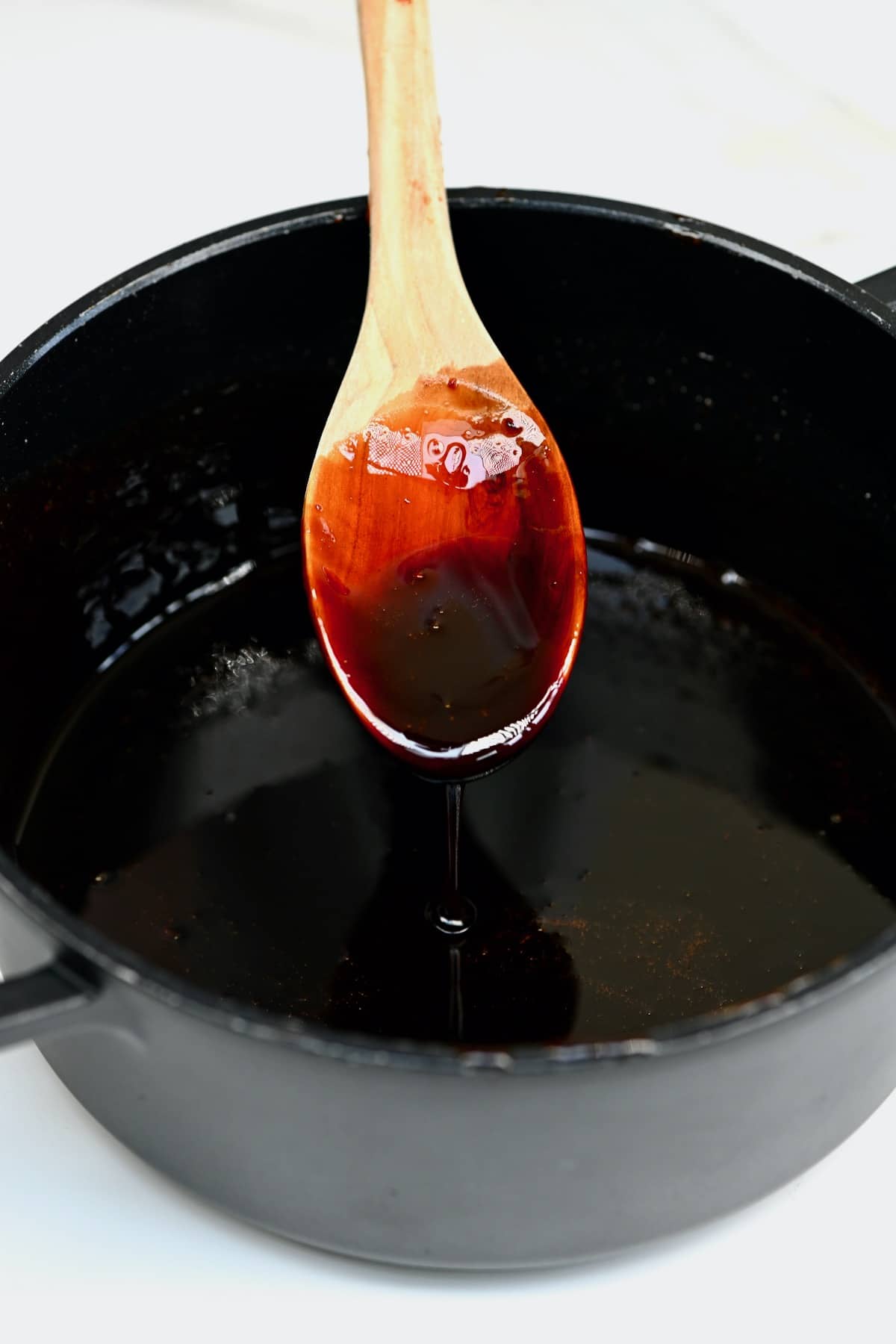 A spoon dripping some date syrup in a pot