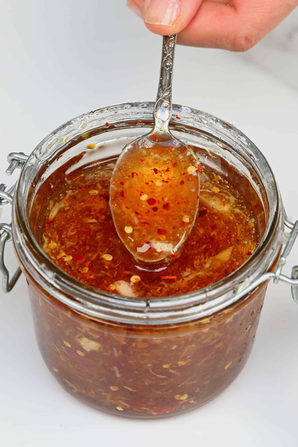 A spoonful of garlic chili honey over a jar