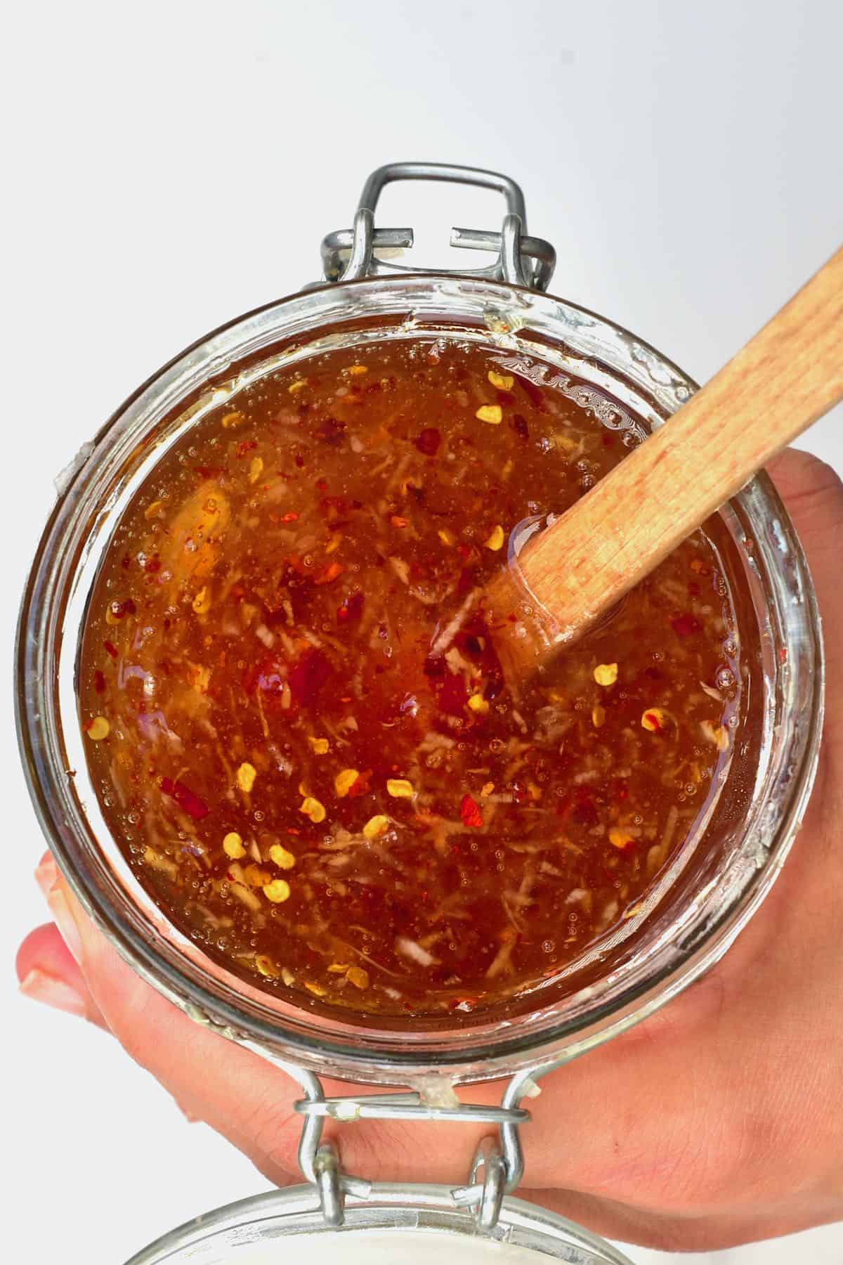 Stirring garlic chili honey in a jar