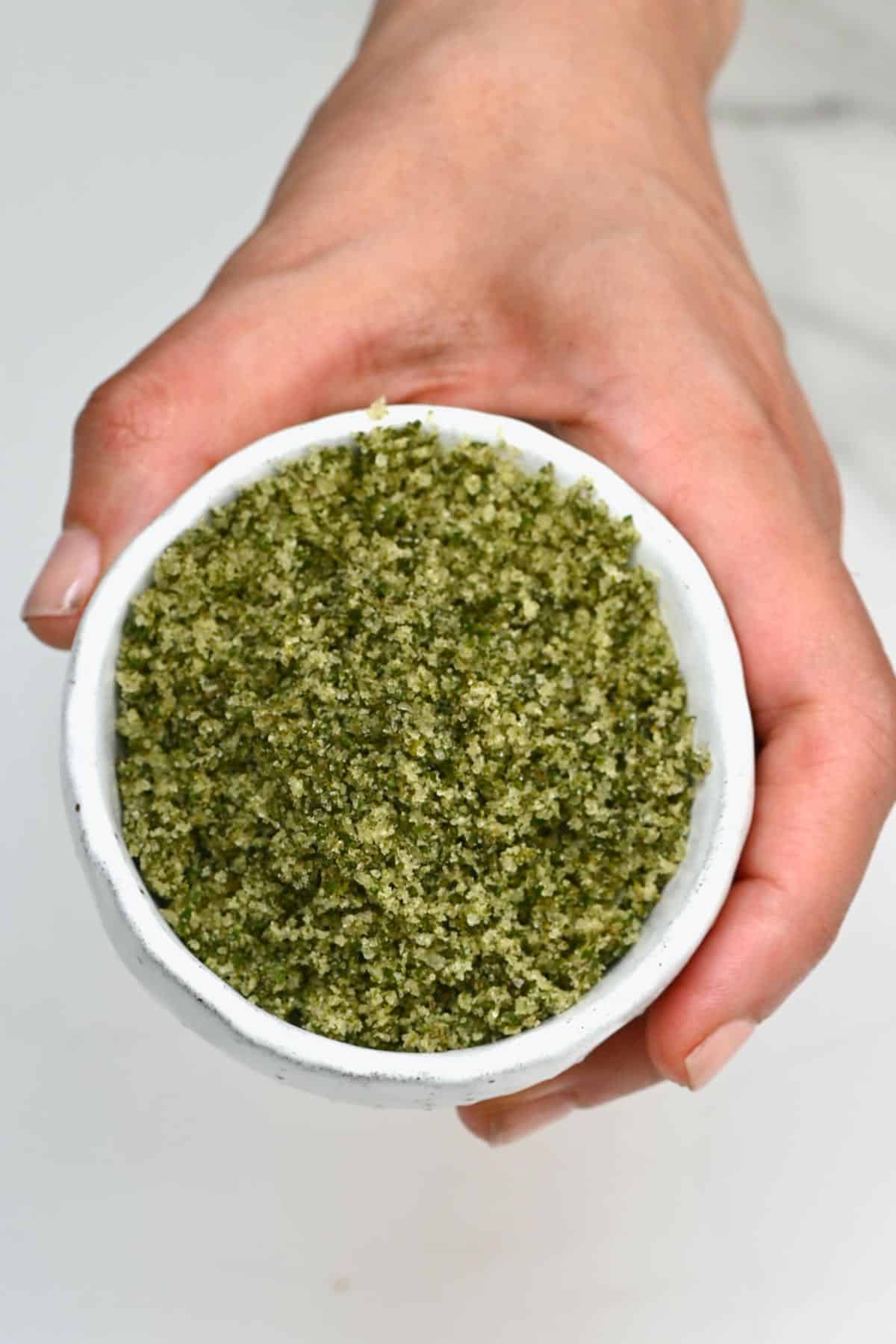 Hand holding a small bowl with herb salt