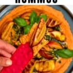 A cracker topped with Roasted red pepper hummus