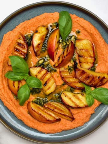 Roasted red pepper hummus topped with grilled peaches and basil