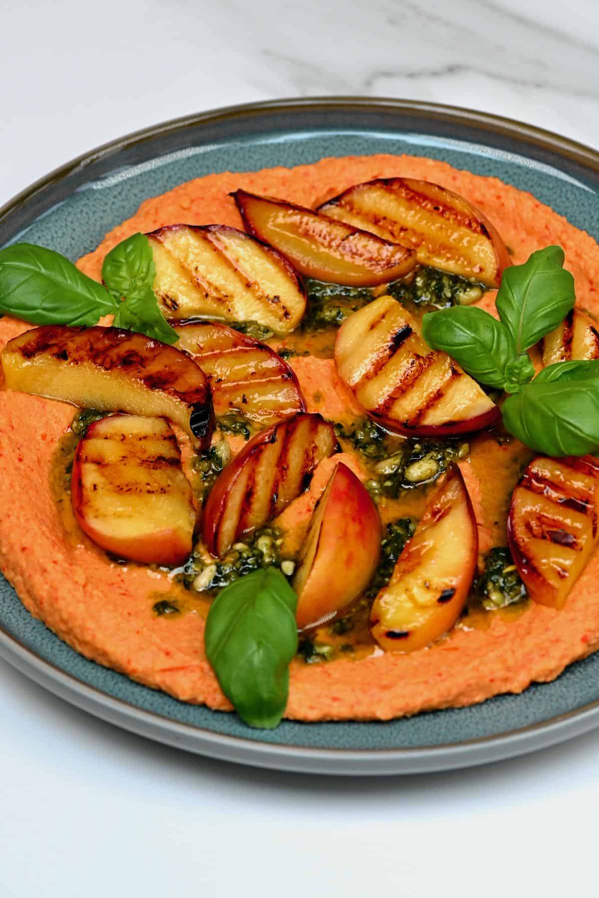 Roasted red pepper hummus topped with grilled peach and basil