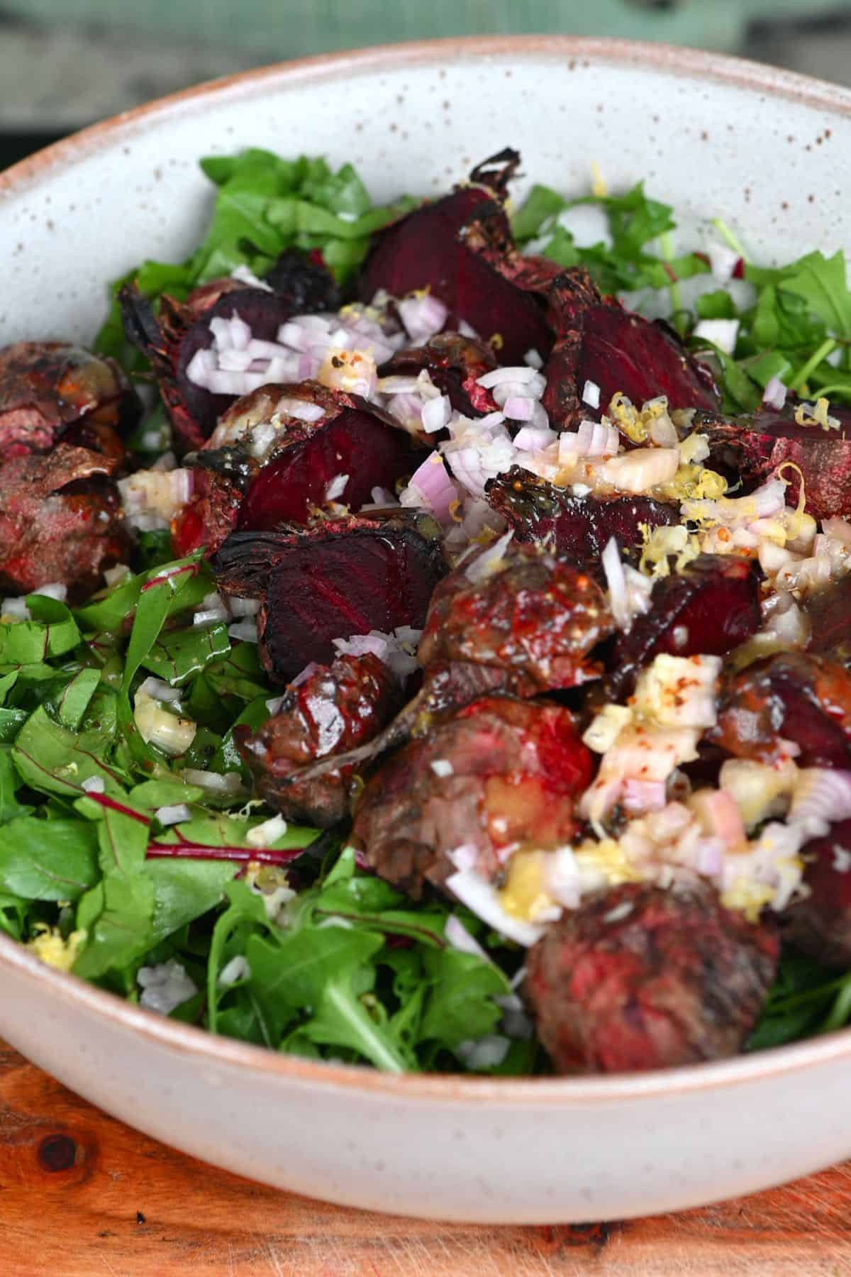 Mixing roasted beet salad in a bowl