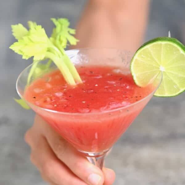 A glass of Bloody Mary topped with celery and lime