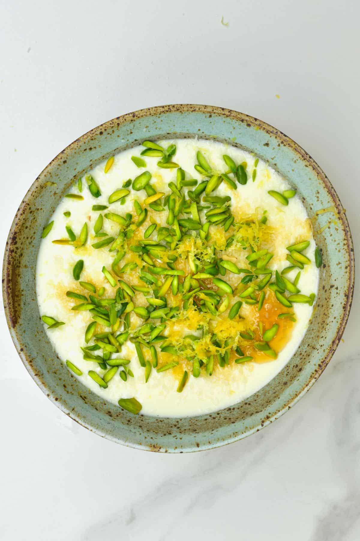 Milk ginger pudding in a bowl topped with pistachios and lemon zest