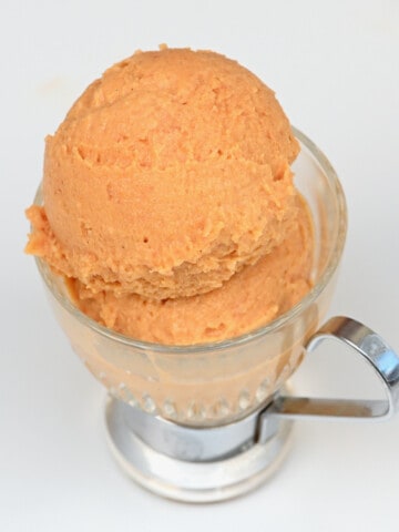 Two balls of peach ice cream in a small cup
