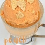 A serving of peach ice cream topped with some ginger crackers