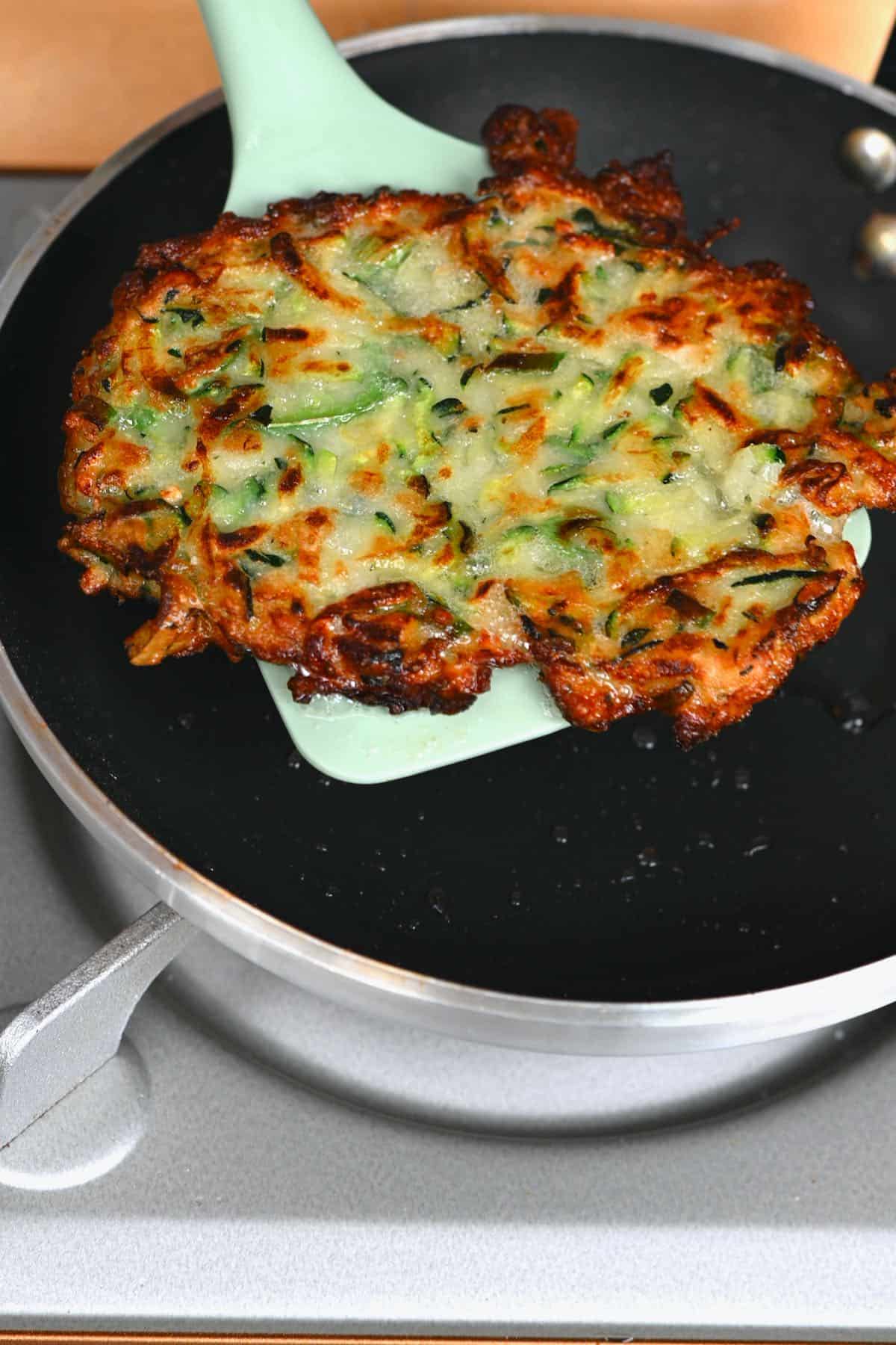 Removing a zucchini fritter from the pan