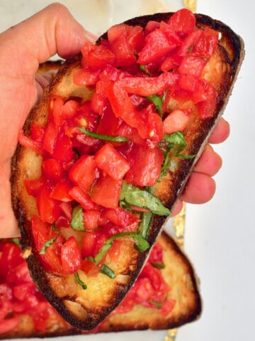 Hand holding a tomato bruschetta