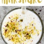Top view of banana milkshake in a glass topped with pistachios