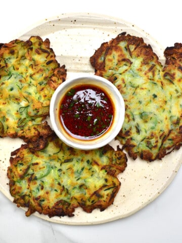 Three Korean Crispy Vegan Zucchini Fritters and dipping sauce on a plate