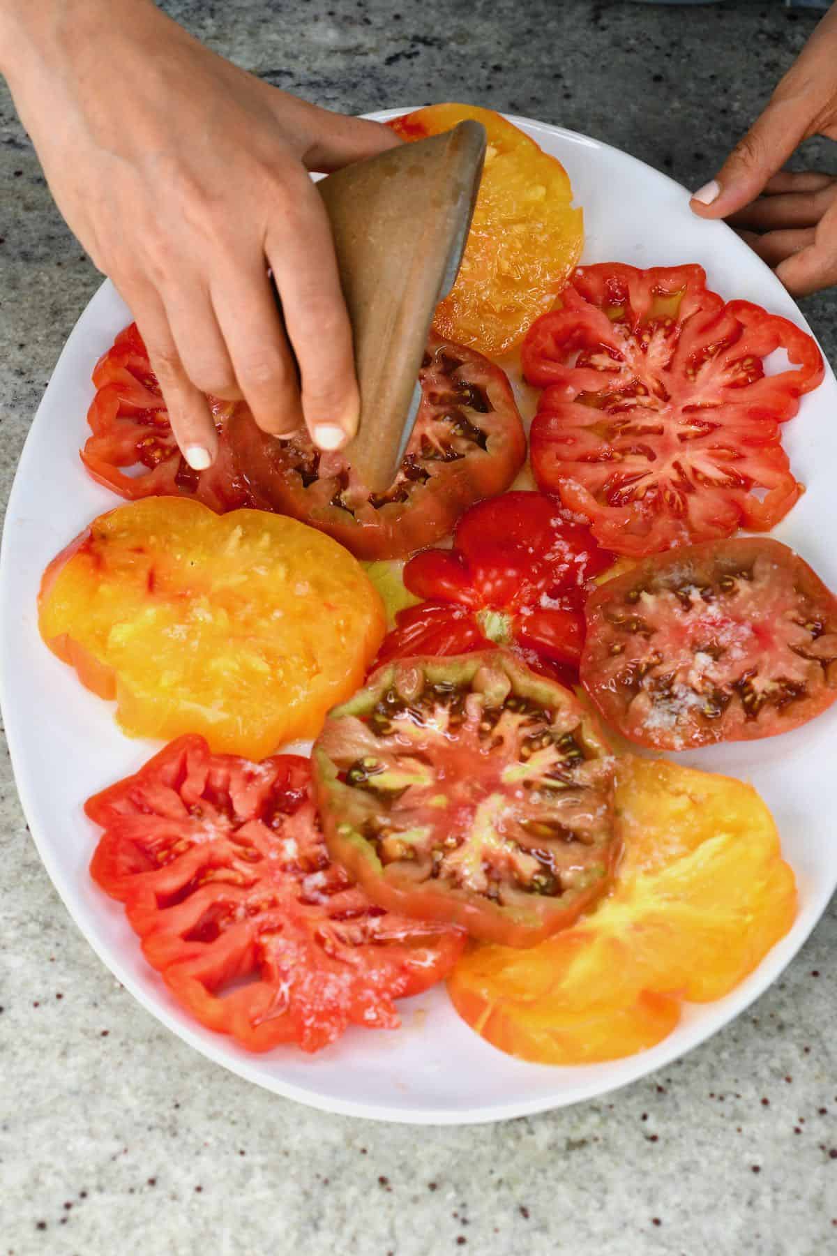 Pouring salad dressing over tomato slices