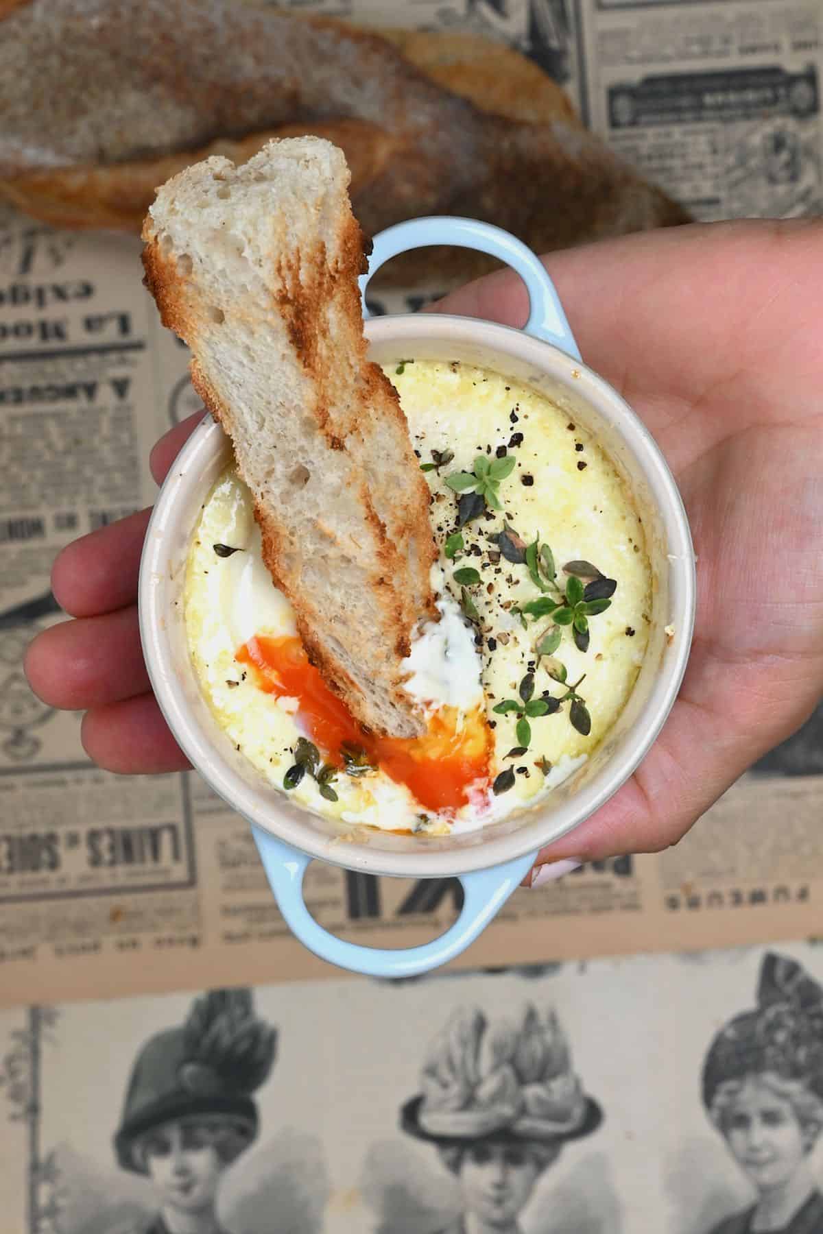 Baked eggs with bread being dipped in