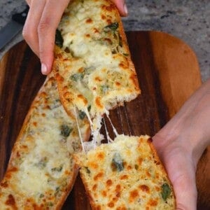A large piece of garlic bread being cut in two