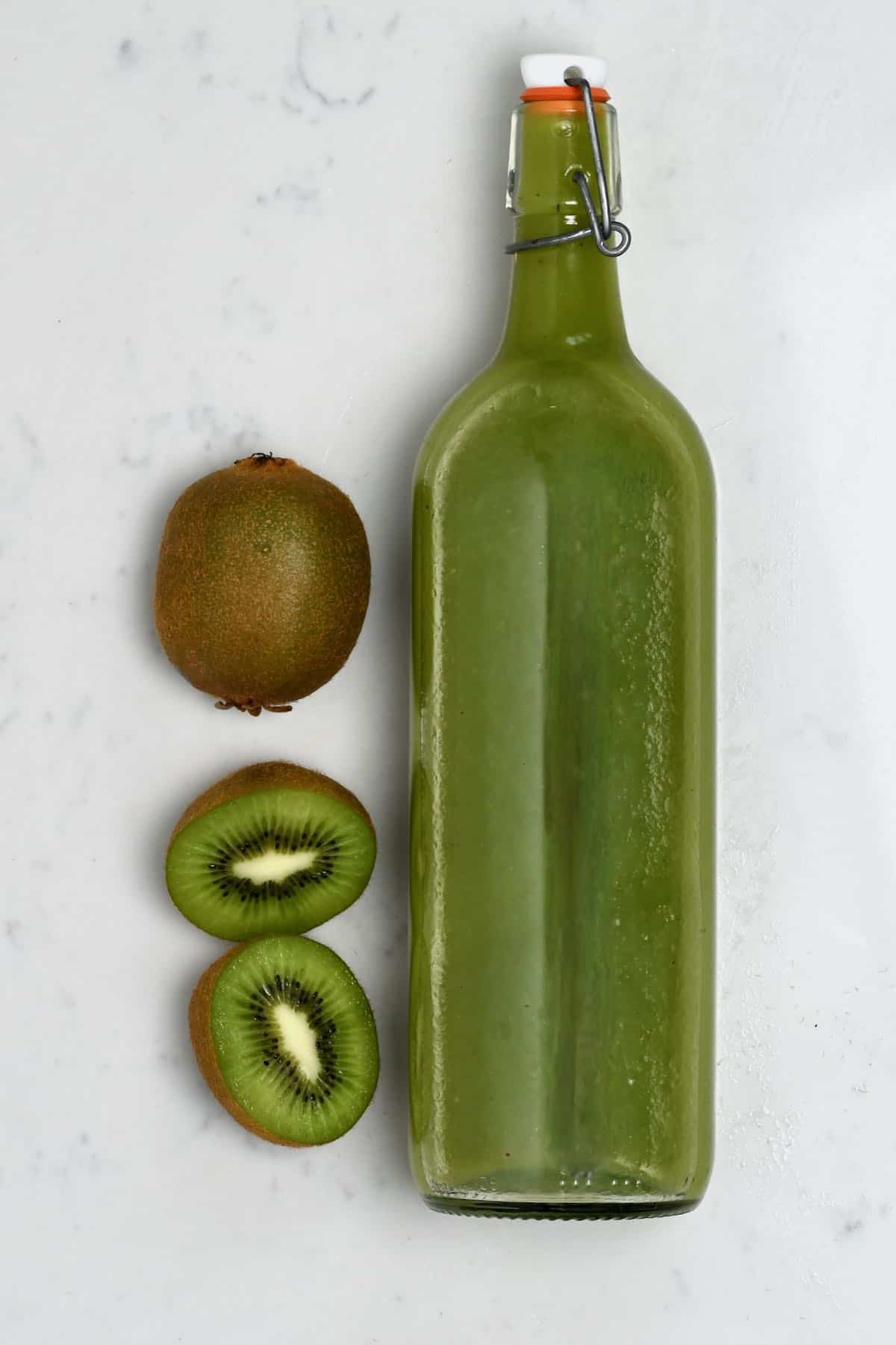 Kiwi juice in a bottle and two kiwis