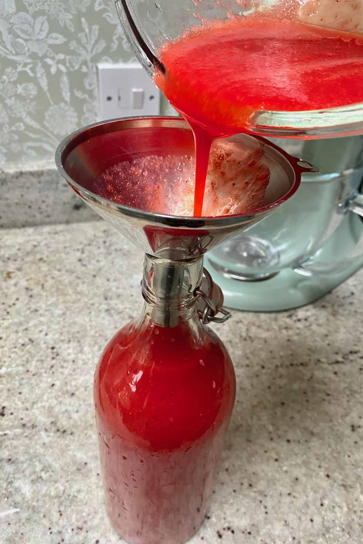 Pouring strawberry juice in a bottle