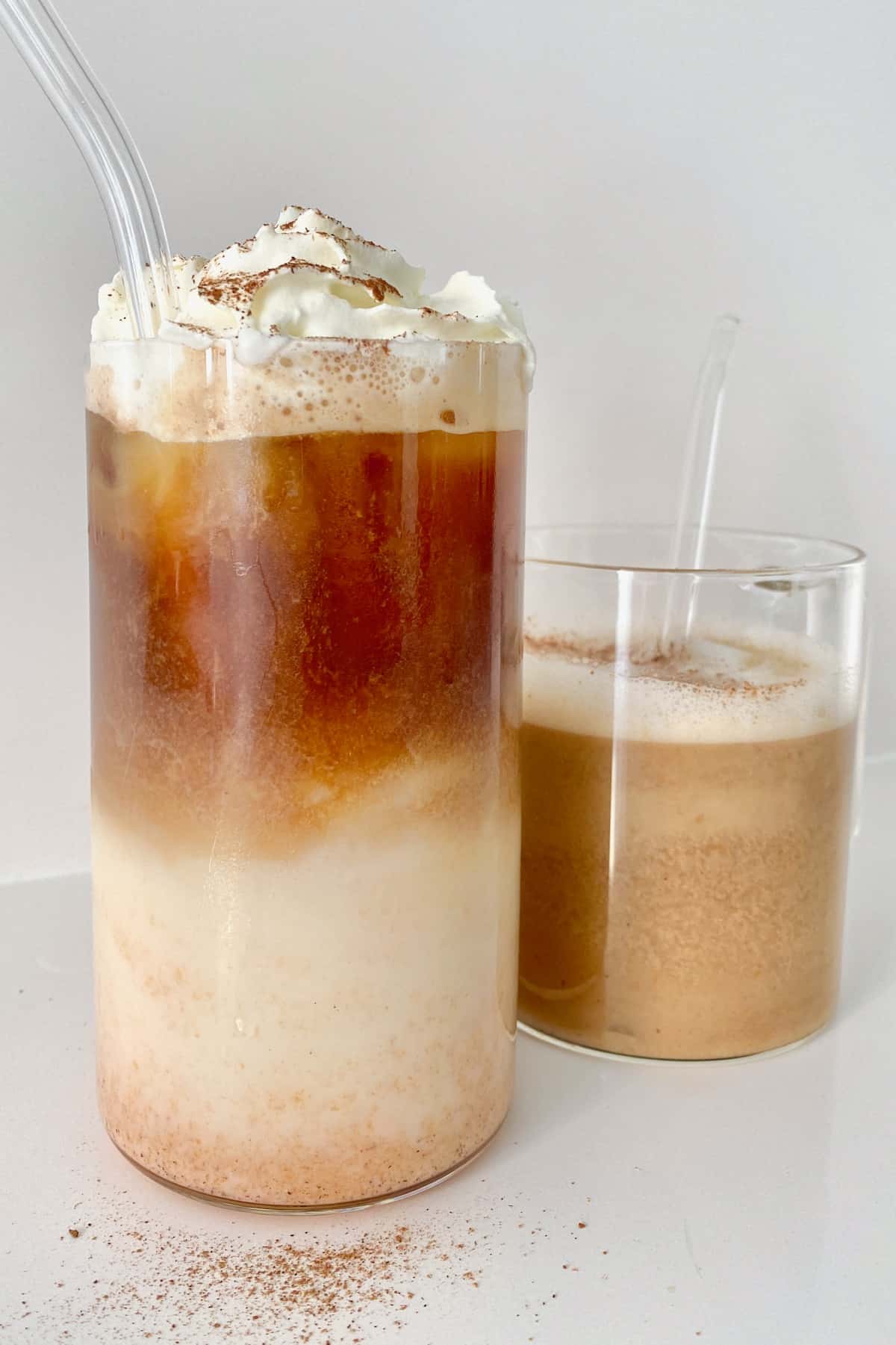 Two pumpkin spice lattes with glass straws