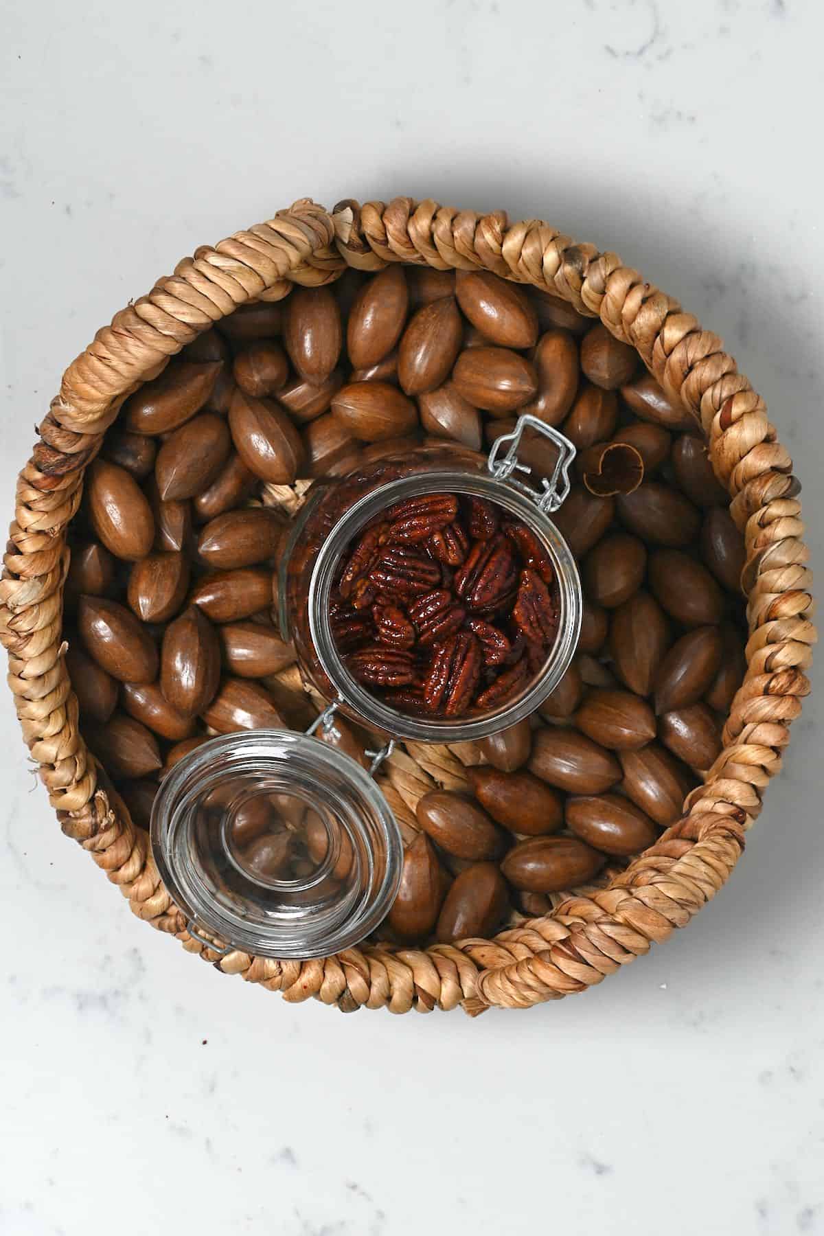 A basket with pecans and a jar with candied pecans